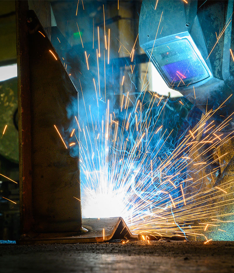 Sudor lucrând la componente metalice în atelierul de producție ISAF
